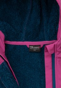Chaqueta forrada de forro polar con un exterior rosa, interior azul, cremalleras y una etiqueta con la marca "TROLLKIDS". Tejidos suaves y texturizados.