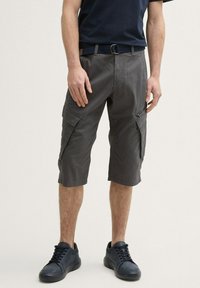 Graue knielange Cargo-Shorts mit mehreren Seitentaschen, Gürtelschlaufen und einem Reißverschlussdetail; der Stoff hat eine glatte Textur mit einem dezenten Muster.