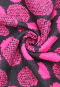 Tessuto a motivo rosa brillante e nero, con grandi pois rosa su uno sfondo nero, caratterizzato da una superficie morbida e texturizzata.