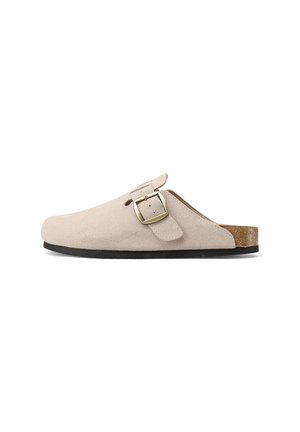 Scarpa clog in suede beige, con punta rotonda, fibbia regolabile e suola in gomma nera. Design minimalista, texture morbida.