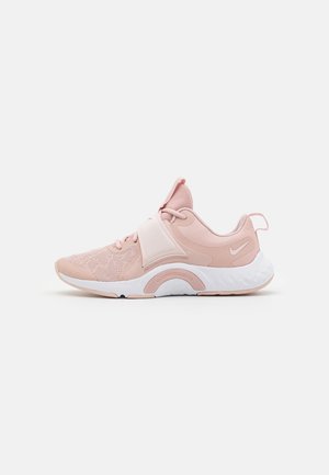 Baskets de sport Nike roses et blanches avec dessus en mesh, fermeture à lacets à l'avant et semelle épaisse et rembourrée, vues de côté sur fond blanc.