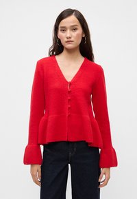 Cardigan roșu, dintr-un amestec de lână, cu decolteu în V, închidere cu nasturi și tiv peplum. Are manșete evazate și detalii cu textură nervurată.