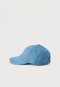 Plava baseball kapa od pamuka s zakrivljenim vizirjem, bočnim otvorima za ventilaciju i kontrastnim izvezenim logotipom na prednjoj strani. Podesivi stražnji remen.