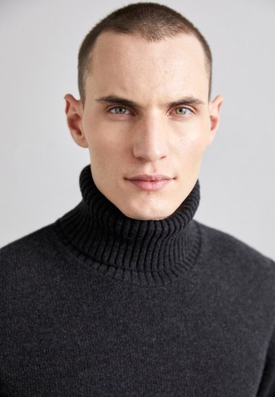 Tamsiai pilkas turtleneck tipo megztinis, pagamintas iš raukšlėtos medžiagos, su aukšta apykakle ir minkšta, lygi tekstūra.