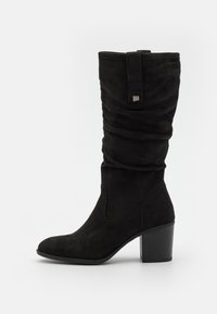 Botte hauteur genou en daim noir avec un design froissé, bout arrondi et talon bloc. Dispose d'une lanière décorative avec un accent en métal.