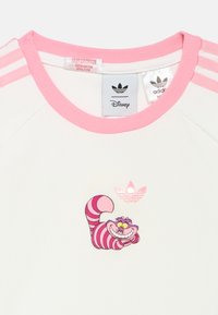 Fehér rövid ujjú ing rózsaszín bordázott gallérral és csíkokkal. Rózsaszínre nyomott Cheshire Macska motívum és Adidas logó díszíti.