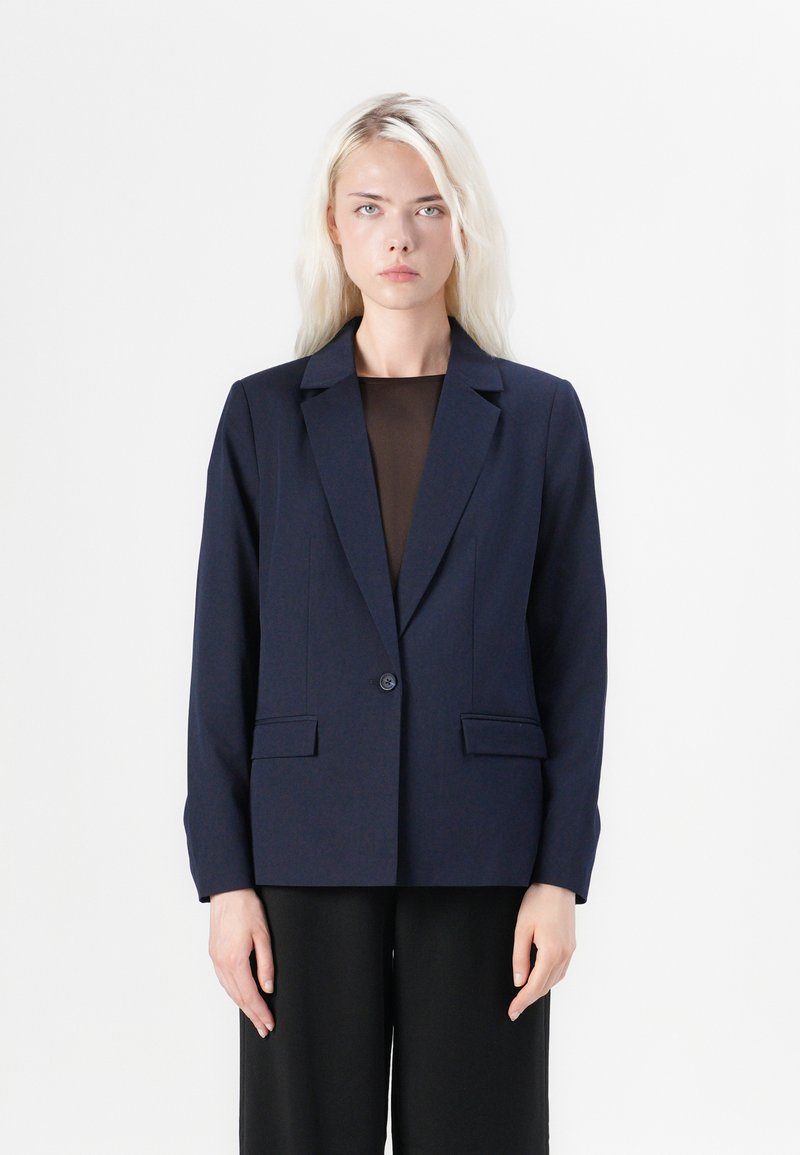 Námořnický blazer s jedním knoflíkem, klopami a dvěma předními kapsami. Střižený střih s hladkým povrchem.