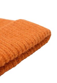 Beanie arancione lavorato a maglia con una texture a coste, dotato di un risvolto. Realizzato in morbido materiale di lana con un aspetto peloso.