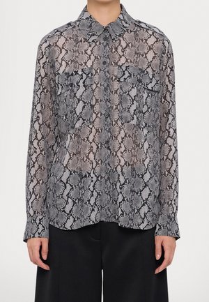 Buttoned long-sleeve shirt with gray and black snake print pattern, two chest pockets, worn with black pants.