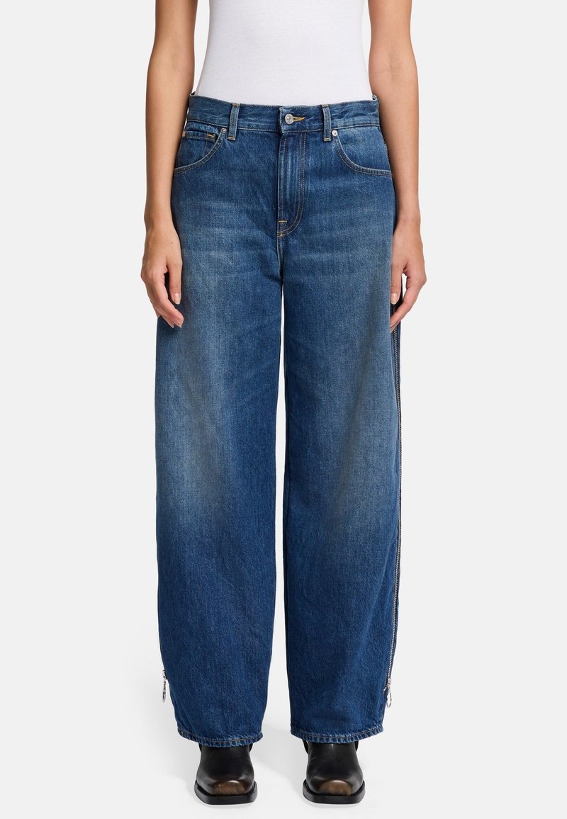 Weite blaue Jeans aus Denim mit einem verblassten Finish, mit seitlichen Reißverschlüssen und einem klassischen Fünf-Taschen-Design. Verfügt über einen Knopfverschluss und Gürtelschlaufen.