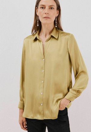 Satin blouse met lange mouwen in olijfgroen, met een spitse kraag, knoopsluiting aan de voorkant en knoopaccenten. Gladde textuur en een ontspannen pasvorm.