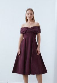 Μπορντό φόρεμα off-the-shoulder από twill ύφασμα, με εφαρμοστό μπούστο, με πλούσιο μπούστο και ντραπέ λαιμόκοψη, σε μήκος μέχρι τα γόνατα.