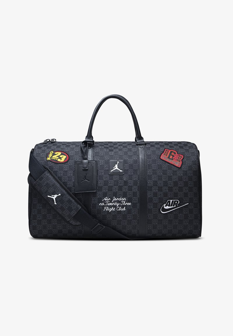 Schwarze Duffel-Tasche mit strukturiertem Muster, Lederakzenten und mehreren Logos. Verfügt über zwei Tragegriffe und einen abnehmbaren Schultergurt.