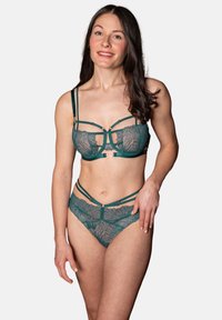 Grüner Spitzen-BH und passende Panties mit aufwendigen Blättermotiven, verstellbaren Details und goldenen Hardware-Accents. Glatte Textur und figurbetonter Schnitt.