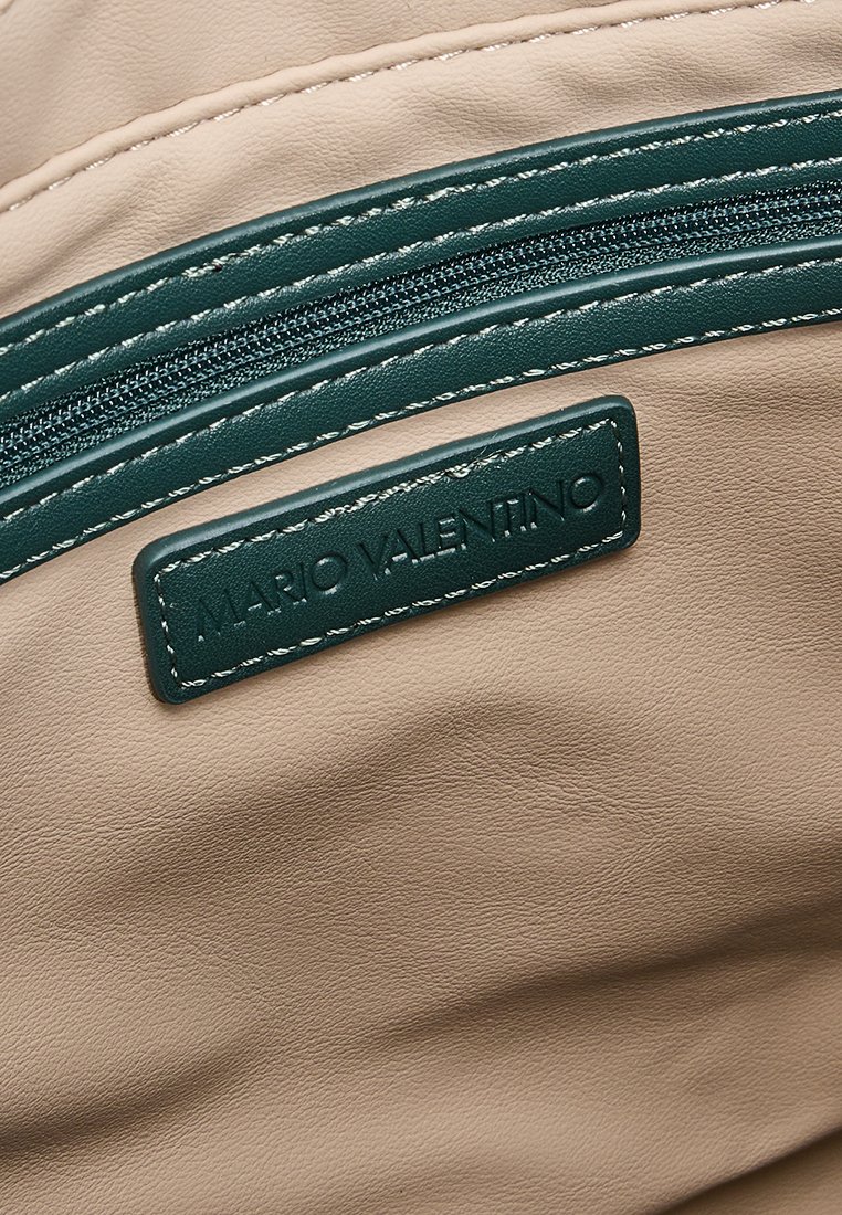 Beige Kunstledertasche mit dunkelgrünem Reißverschluss, ausgestattet mit einem rechteckigen Anhänger mit dem geprägten Schriftzug "MARIO VALENTINO" und kontrastierendem weißen Nähten.