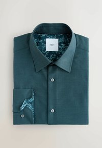 Chabrowa koszula z guzikami i teksturowaną powierzchnią. Podszewka rękawów i kołnierza w kwiatowy wzór, z metką "NEXT". Dwa widoczne guziki z przodu.