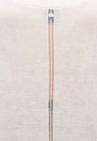 Pleteni pulover svetlo kremne barve z teksturiranim vzorcem. Ima vertikalni, delno odprt zadnji šiv z na vrhu nameščenim kovinskim gumbom.