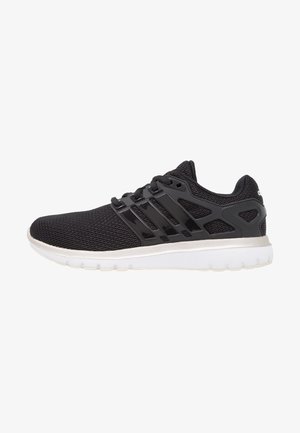 Zapatilla de correr de malla negra con cordones negros, superposiciones de plástico negro y suela blanca vista desde el lado derecho sobre un fondo blanco.