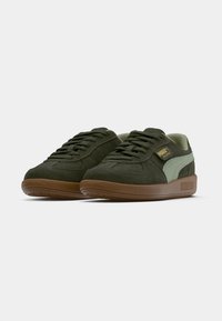 Adidași din suede verde, cu un logo PUMA de un verde deschis, vârf rotund și talpă din cauciuc. Prezintă detalii texturate la șireturi.