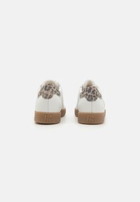 Vita sneakers med ett leopardmönster på hälen, brun gummisula och strukturerad yta. Enkel och modern design.