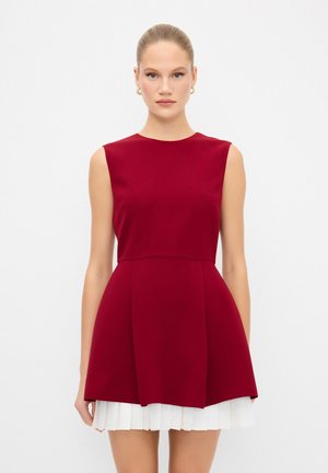 Burgundy ilmanhiha dress, jossa on istuva yläosa, levenevä hame ja valkoiset poimutetut yksityiskohdat helmassa. Silkkinen kangas ja siisti siluetti.