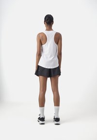 Fehér ujjú nélküli póló, fekete sort, fehér bokazokni és fekete sportcipő. Minimalista dizájn, puha anyag és sportos illeszkedés.