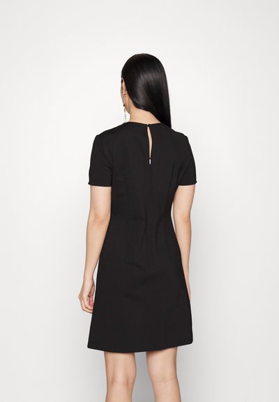 Robe noire à manches courtes avec un corsage ajusté et une jupe évasée, présentant une ouverture en forme de clé au dos et une texture de tissu lisse.