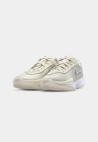Lys grå sportssko med mesh og syntetisk overdel, tekstureret gummi sål, polstret krave og fremtrædende Nike swoosh-logo.