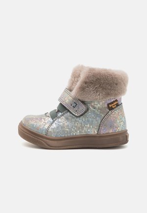 Botte d’hiver pour enfant à motif mosaïque argenté, semelle marron, bride en Velcro, lacets élastiques verts et doublure en fourrure beige et moelleuse autour de la cheville.