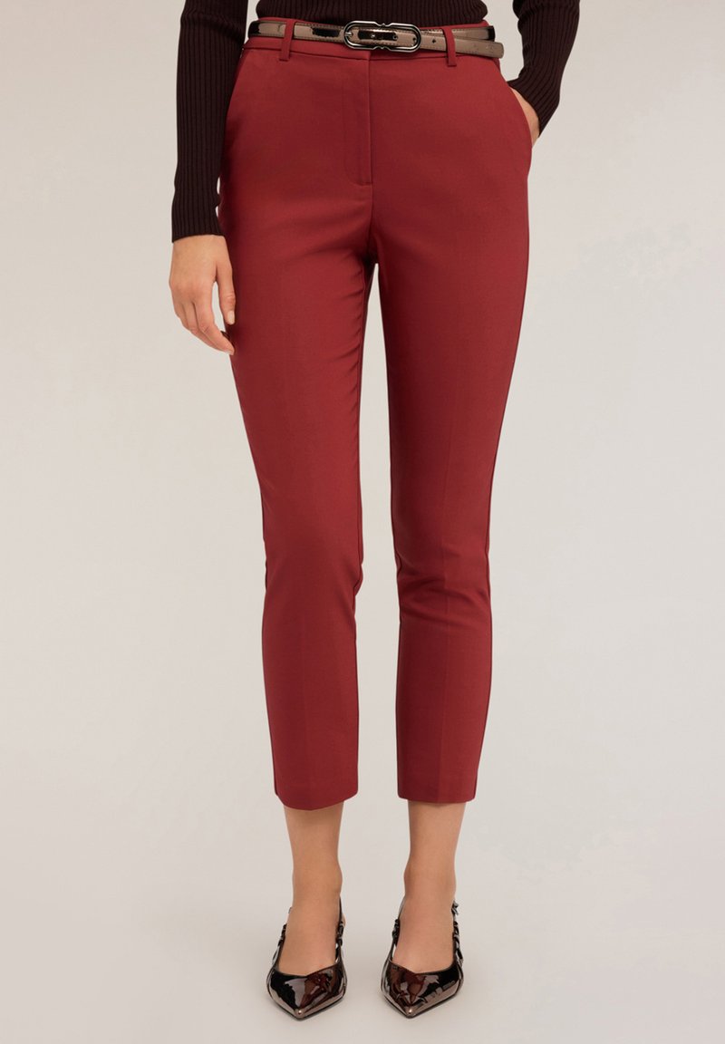 Röda skräddarsydda byxor med en jämn textur, kort längd och smal passform. Matchas med ett glansigt svart bälte och spetsiga klackar.