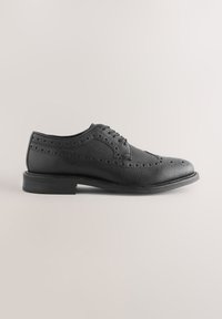 Chaussure brogue en cuir noir avec une finition texturée, des perforations décoratives et un bout arrondi. Dotée d'une semelle plate en caoutchouc et d'une fermeture à lacets.