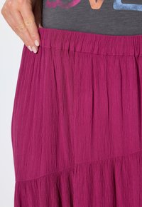 Fuchsia Rock aus zerknittertem Stoff, mit einem strukturierten Taillenbund und fließendem Design mit gerafften Paneelen.