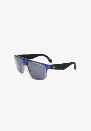 Occhiali da sole rettangolari con lenti grigio scuro, frontale della montatura sfumato dal blu al trasparente e aste nere con logo Adidas trefoil bianco.