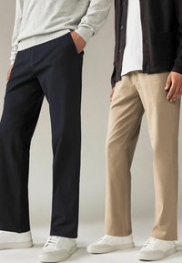 Khaki en marineblauwe broeken met een rechte pijpontwerp in katoenstof; beide in combinatie met witte sneakers en gelaagde tops.