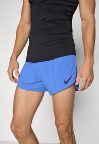 Nike Sportshorts in Blau mit schwarzem Logo, aus leichtem Material gefertigt. Sie verfügen über einen Bund und seitliche Schlitze für mehr Bewegungsfreiheit.