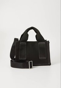 Crna torba od tkanine s dva kratka držača, odvojivim remenom, bijelim šavovima i prednjim džepovima. Jednostavan kvadratni dizajn, bez vidljivih logotipa.