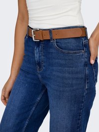 Rudas odinis diržas su sidabrine metaline sagtimi, dėvimas ant mėlynų džinsų. Diržas turi lygų paviršių ir reguliuojamą dydį su keliais skylučių skylutėmis.