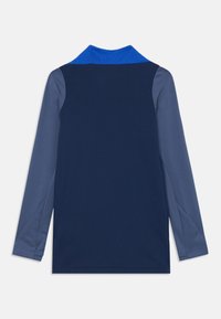 Chemise à manches longues bleue marine avec un col bleu, présentant des manches grises contrastantes. Texture lisse, design décontracté et coupe ajustée.