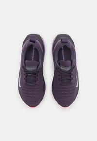 Fioletowe buty sportowe z teksturowaną dzianinową cholewką, czarno-różowymi akcentami, okrągłym noskiem i sznurowanym zapięciem. Z białym logo po bokach.