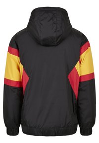 Veste à capuche noire avec des bandes diagonales rouges et jaunes sur les manches et le haut du dos, poignets et taille élastiques, vue de dos.