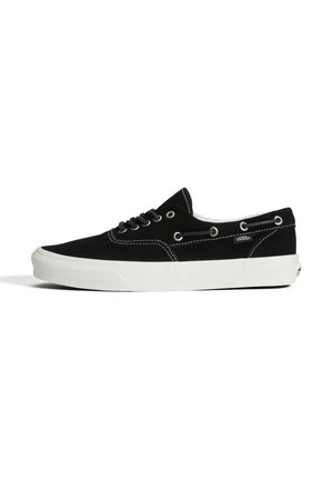 Baskets basses noires avec semelle blanche, lacets à l'avant, œillets métalliques, étiquette Vans sur le côté et surpiqûres blanches contrastantes.