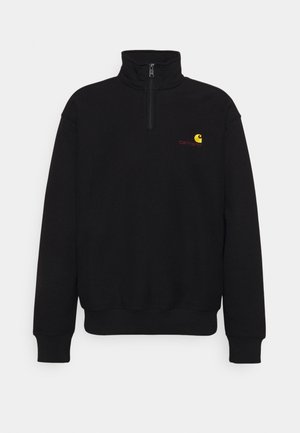 Sweatshirt en polaire noir avec col haut, fermeture éclair mi-longue, poignets et taille côtelés. Présente un petit logo jaune et rouge sur la poitrine.