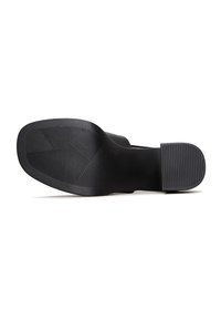 Semelle d'une chaussure noire avec des motifs géométriques texturés à l'avant et des lignes horizontales au talon pour l'adhérence et la résistance au glissement.