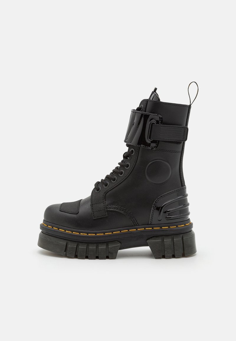 Botte de combat noire montante avec semelle épaisse et robuste, lacets à l'avant, sangle à la cheville et languette à l'arrière sur un fond uni.