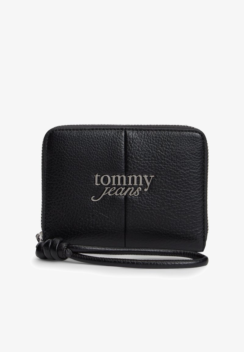 Μαύρο πορτοφόλι καρπού από υφή δέρματος με ασημί λογότυπο "tommy jeans" και κλείσιμο με φερμουάρ.