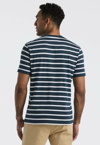 T-shirt rayé bleu marine et blanc en coton, avec des manches courtes, un col rond et une coupe décontractée. Longueur ajustable à l'ourlet.