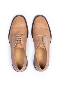 Chaussures habillées en cuir tan avec des détails perforés, bout rond et semelle foncée contrastante. Les lacets sont beiges. L'intérieur est embossé avec la marque.