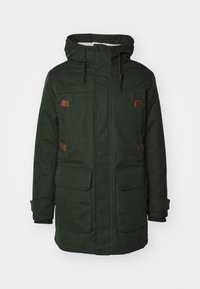 Zeleni vodootporni parka sa kapuljačom obloženom krznom, dva velika prednja džepa, smešnim kožnim detaljima i podesivim vezicama.