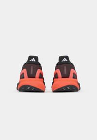 Zwarte en oranje sport schoenen met een gestructureerde bovenkant, gevoerde hak en duurzame rubberen zool. Bevat het Adidas logo op de hak.