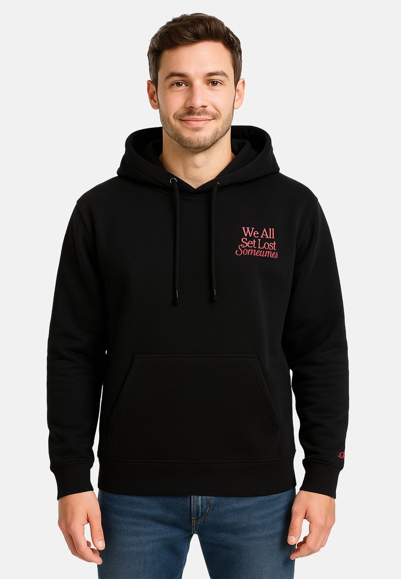 Smiling man wearing a black hoodie with a front pocket and red text on the chest reading "We All Get Lost Someumes."